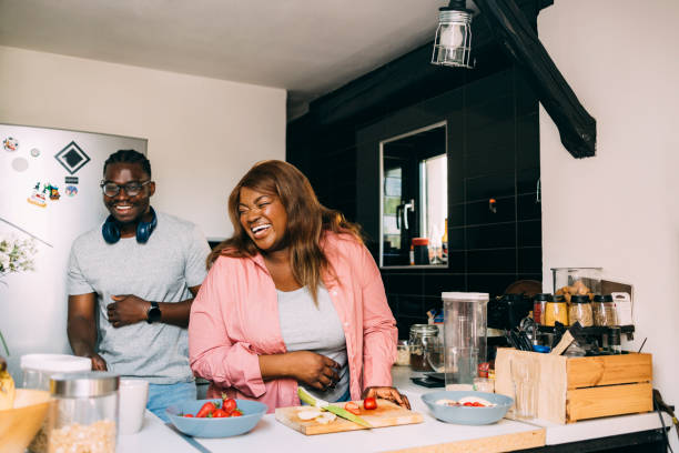 A Happy Couple Laughing While Preparing Breakfast Together
