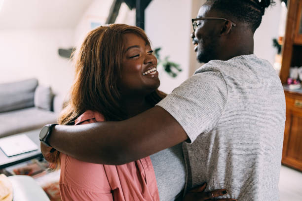 A Beautiful Woman And Her Boyfriend Hugging Each Other And Being Happy To Be Together Again Family members meeting after a long time: a smiling African-American female being embraced by her loving brother. overweight surprised woman stock pictures, royalty-free photos & images