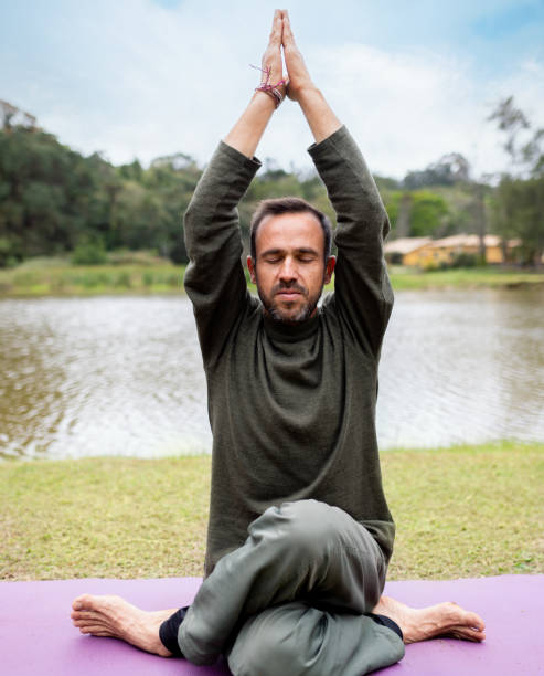 istock Man practicing the sitting tree pose during a yoga session outdoors 1460920634