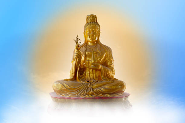 Golden Guan Yin is meditating in heaven. Meditating Golden Guan Yin statue on blue sky background reflecting golden light as if in heaven. kannon bosatsu stock pictures, royalty-free photos & images