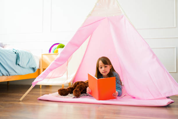 istock Cute girl enjoying reading a book in a tipi 1460932648