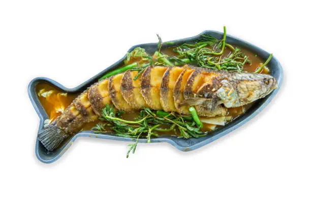 Photo of Top view of Deep fried snakehead Fish in Spicy Sour Soup, focus selective