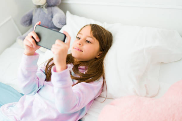 istock Adorable girl kid using her phone in pajamas 1460933651