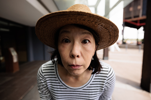 Close-up of an Asian woman with hat staring into the camera