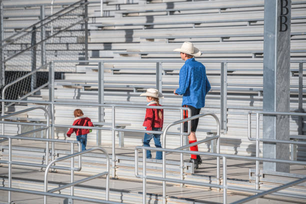 cowboy marchant sur les gradins d’une arène de rodéo avec deux enfants - sport parent bleachers family photos et images de collection