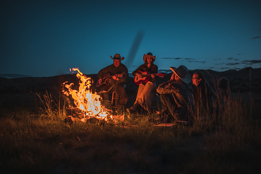 Western american family gathering next to a campfire. They are listening to stories and sharing memories.