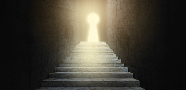 Ladder leading to success behind the keyhole door in the dark room. Light and shiny growing through from key hole. Business key way to success concept