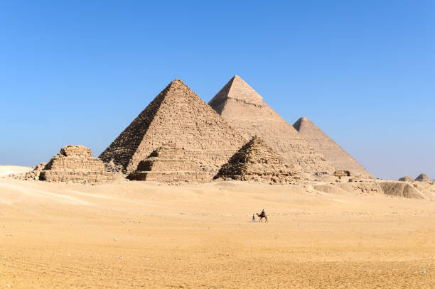 il grande complesso piramidale di giza con carovana di cammelli che cammina di fronte alle piramidi egiziane - giza - cairo - egitto - giza foto e immagini stock