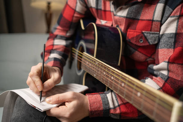 istock Close-up of composer writing and examining sheets with notes for guitar. 1460953186