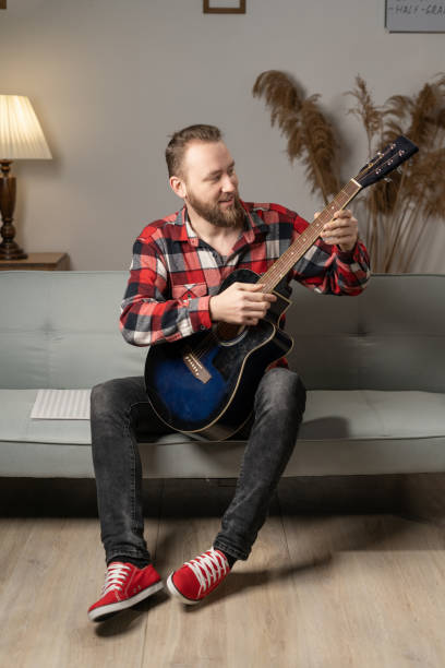 istock bearded man sits at home playing acoustic guitar in the evening. 1460953199