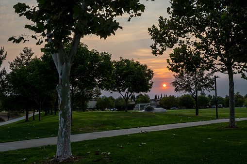 Davis, CA. Sunset at the Arroyo Park wtih orange hues, showing the grass, the bike path, the soccer field