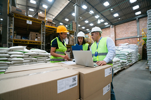 Group of Latin American workers working together at a distribution warehouse and planning some shipments