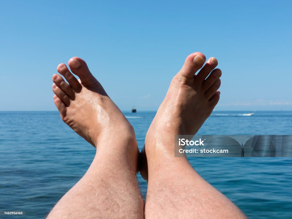 Feet pointing at the sea Relaxed male feet pointing at the Adriatic Sea at Rovinj, Croatia Adult Stock Photo