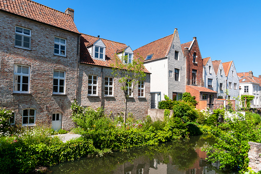 Brugge : houses at the edge of the canal, reflected in water, in Brugge, Belgium. May 27th, 2022.