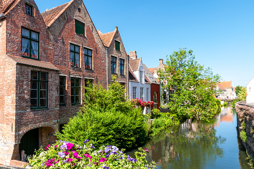 Brugge : houses at the edge of the canal, reflected in water, in Brugge, Belgium. May 27th, 2022.