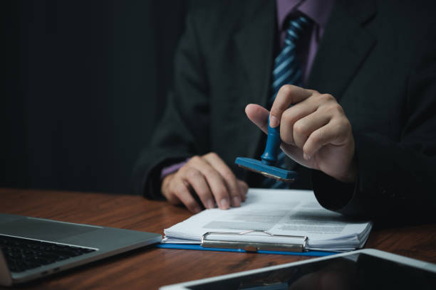 istock Man hand stamping approval signing on document or paperwork contract at desk. 1460958171