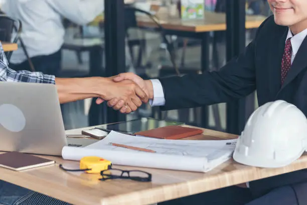 Photo of Team Business Partners shaking hands together to Greeting Start up small business in meeting room. Shakehand teamwork partners at modern office handshake together. Business mergers and acquisitions