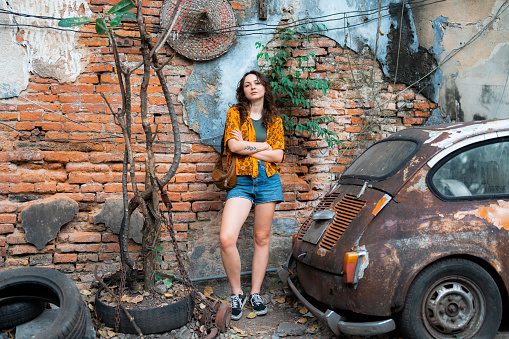 Young Caucasian woman standing on the background of the wall in Chinatown near old car