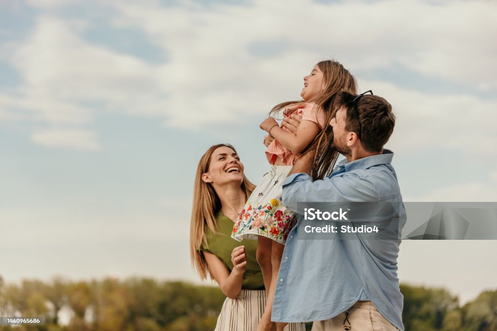 Seeing your daughter happy is a remarkable feeling Loving parents walk and lift their loving children on the sand at the beach on a sunny day. lifestyle and weekend. Copy space Family Stock Photo