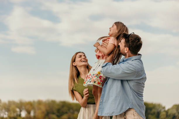 Seeing your daughter happy is a remarkable feeling Loving parents walk and lift their loving children on the sand at the beach on a sunny day. lifestyle and weekend. Copy space family stock pictures, royalty-free photos & images