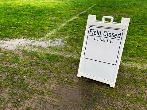 Field Closed Do Not Use sign on green lawn at a public park due to weather conditions.