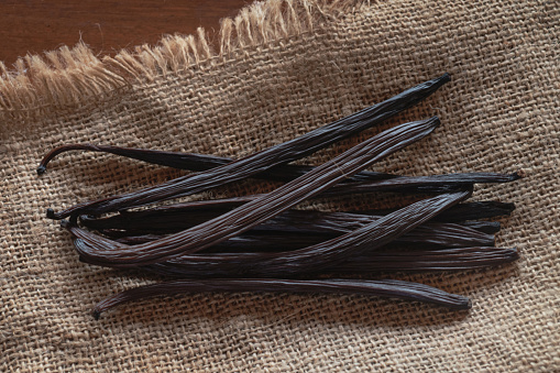 Dry vanilla beans on sack texture background brown, aromatic vanilla sticks, view from above