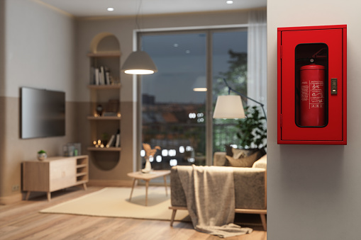 Close-up View Of Fire Extinguisher Cabinet On Wall With Blurred Living Room Background