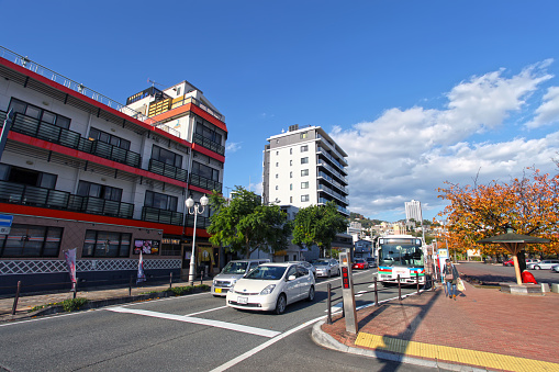 Street scene at a road junction in Atami City, Shizuoka, Japan with hotels and apartment buildings and a blue sky.