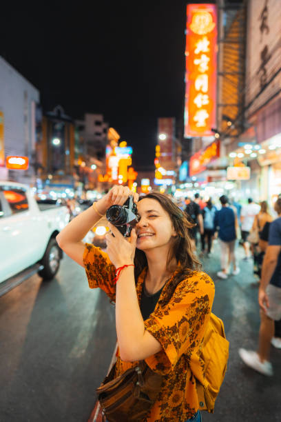 Woman photographing with camera in Chinatown, Bangkok Cheerful young Caucasian woman photographing with camera in Chinatown, Bangkok photographic film camera stock pictures, royalty-free photos & images