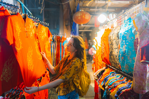 Young Caucasian woman choosing Chinese dress in Chinatown in Bangkok