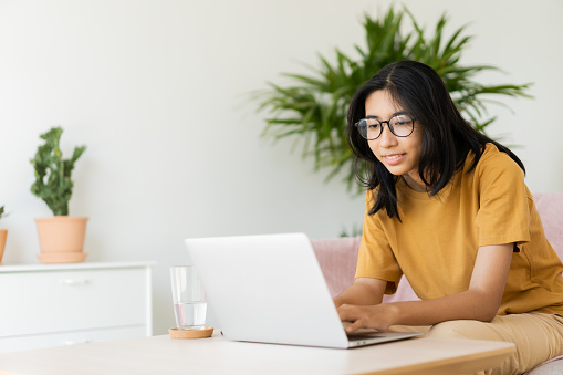 Asian woman wear glasses typing work on laptop.