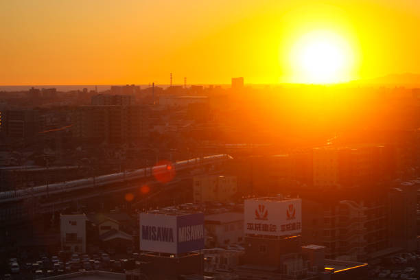 Sunset over Mishima city in Shizuoka Prefecture, Japan. Sunset over Mishima city in Shizuoka Prefecture, Japan with view of the horizon over the sea, silhouetted buildings and a Shinkansen bullet train. misawa japan stock pictures, royalty-free photos & images