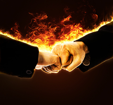 Their deal is on fire! Woman and man in business suits catch fire as they fist-bump.
