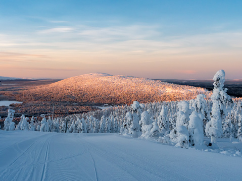 Nordic nature during winter. Snow and beautifully colored sun light on mountain side.