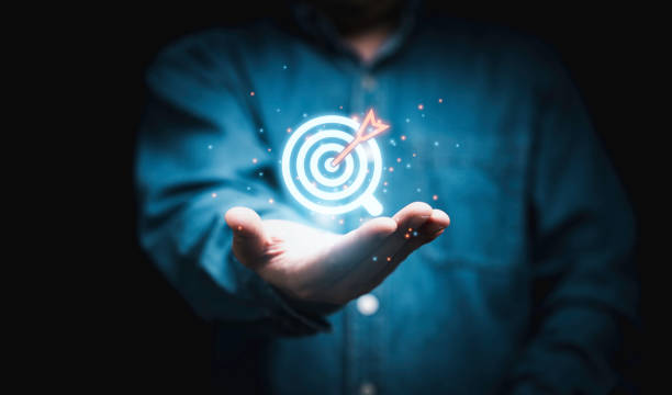 istock Businessman holding glowing virtual blue quality dartboard with red arrow for setup quality objective target and goal concept. 1460985651