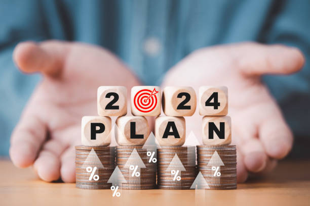 Businessman hand give wooden block cube 2024 with dartboard on coins stacking for setup objective target business cost and budget planing of new year concept.