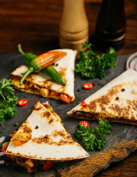 Quesadilla with chicken and hot peppers, curly parsley leaves and two bottles of hot sauce. stock photo