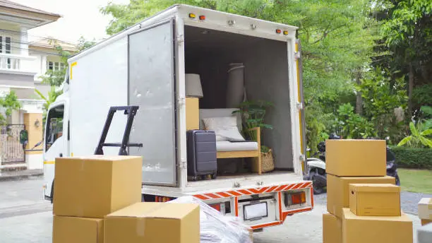 Photo of Truck car moving house for customers, delivering boxes and furniture. Vehicle transportation. Shipping and packaging business occupation service company. People lifestyle.