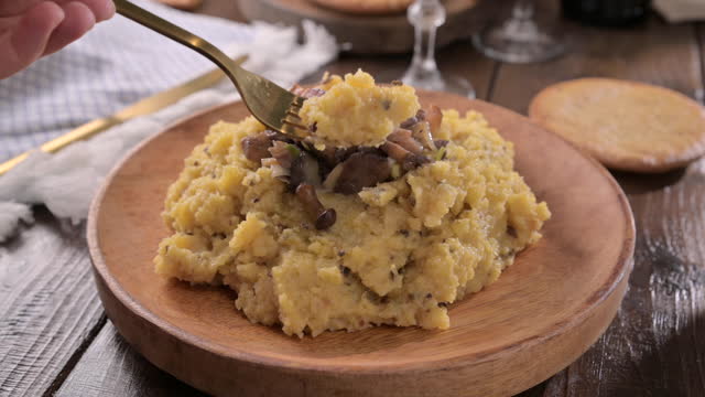 polenta with porcini mushrooms, bacon, served on a dark wooden background with a