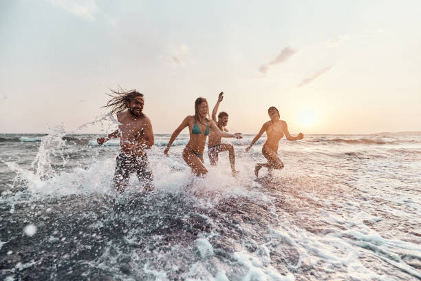 istock Cheerful couples having fun while running out of sea at sunset. 1460995244