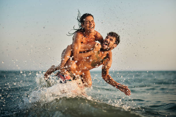 Young playful couple having fun while piggybacking at sea.