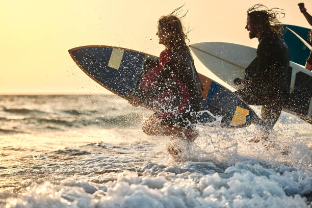 istock Carefree surfers having fun while rushing to surf at sunset. 1460995826