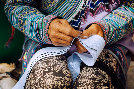 Mujer vietnamita hmong ocupada cosiendo coloridas telas tradicionales photo