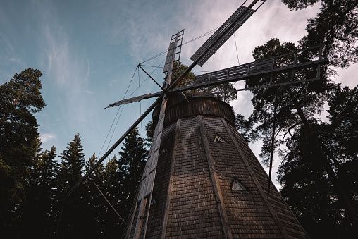 A low angle shot of the windmill surrounded by trees.