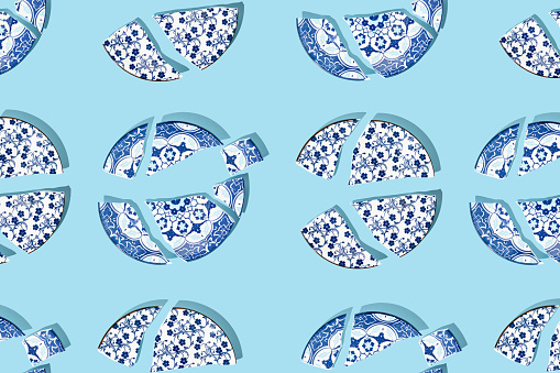 Pattern with broken china porcelain plates on blue background. Minimal concept.