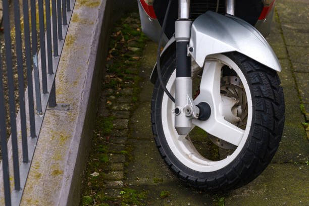istock The front wheel of a motor scooter standing on the sidewalk. 1461002189