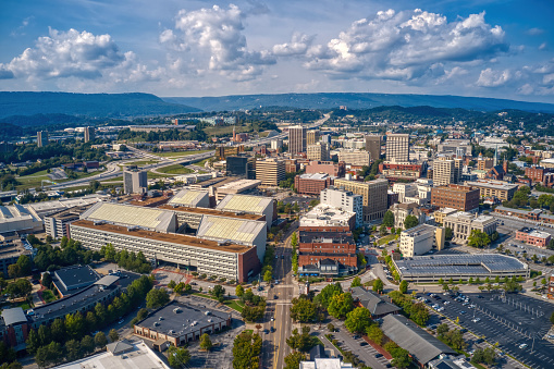 An aerial view of downtown Chattanooga with dense buildings under a blue sky with fluffy clouds