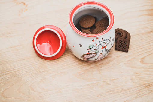 cocoa and chocolate cookies in a finely decorated stoneware jar on a rough wood tabletop with text space