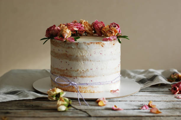 istock White cream cake decorated with fresh flowers on a wooden table 1461003396