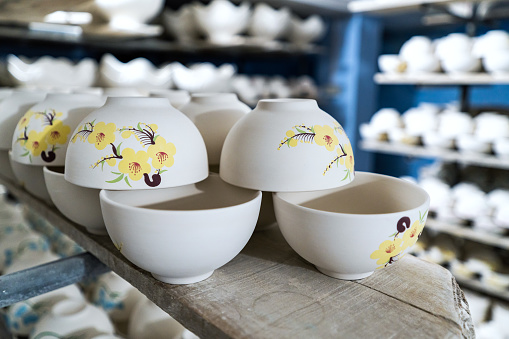 Handmade ceramic ceramics with glaze and without glaze. Pitchers and pots dry on shelves in a pottery workshop before the firing process.